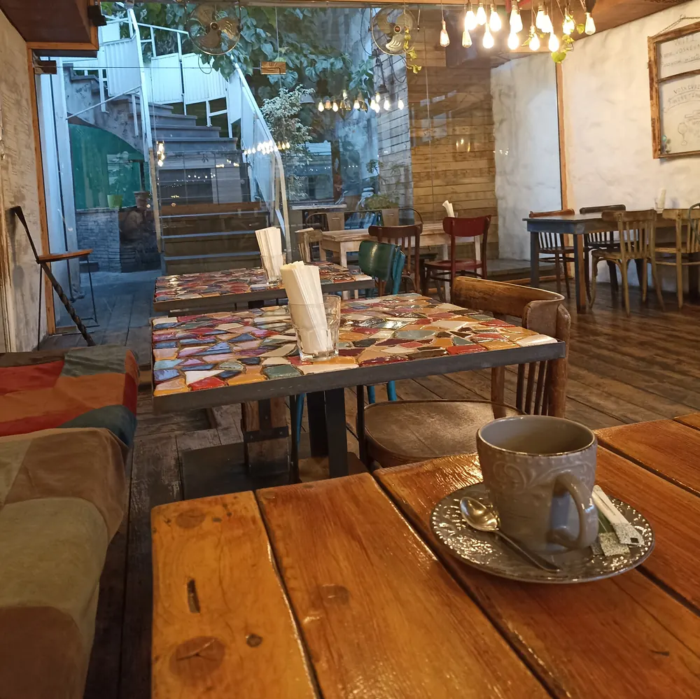 A cup of coffee on a wooden table in the lower room, the street steps behind