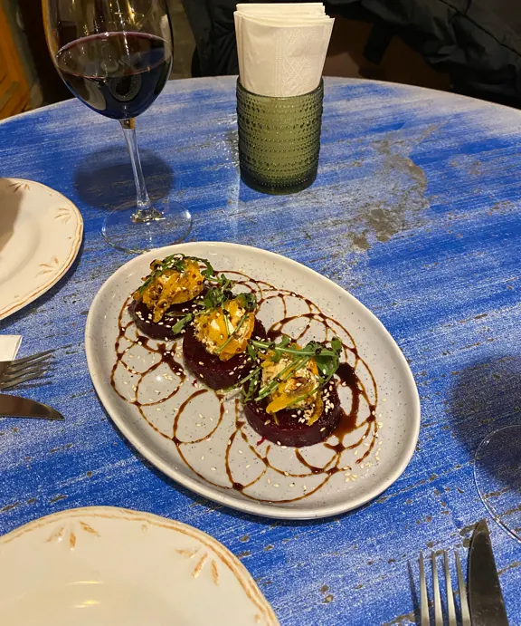 A cold starter and a glass of red on one of the blue tables