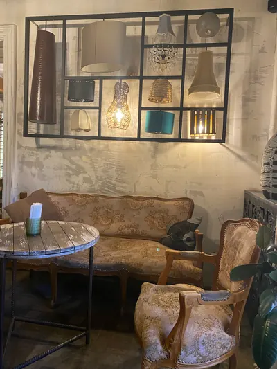 An old carved sofa and armchair under a wall of hanging lamps