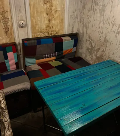 A turquoise wooden table and a patchwork sofa against a carved plaster wall